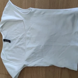 Vit ärmlös topp - Säljer en enkel och stilren vit ärmlös topp.Toppen har en rund halsringning och är tillverkad i mjukt bomullsmaterial. Perfekt att matcha med jeans eller kjol.