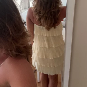 Ljusgul volangklänning  - Supersöt ljusgul klänning med flera plisserade volanglager och smala axelband. 