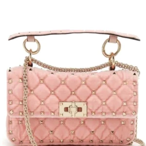 Rosa quiltad axelväska med kedja - Säljer en snygg rosa axelväska med quiltat mönster och guldfärgade nitar. Väskan har en kedjerem och ett dekorativt spänne framtill. Perfekt för dig som vill ha en trendig accessoar med lite edge.