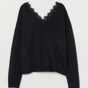 Svart stickad tröja med spetsdetalj - Svart stickad tröja med djup v-ringning och fin spetskant längs halsen. Långärmad modell med avslappnad passform, perfekt för lager-på-lager och snygg till både jeans och kjol.