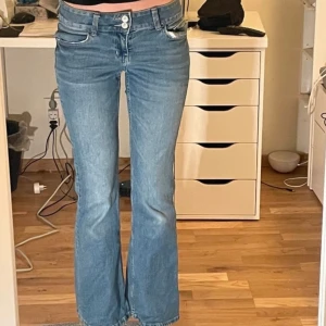 Lågmidjade blå bootcut jeans med broderade bakfickor - Säljer ett par snygga blå bootcut jeans med broderade detaljer på bakfickorna, från H&m. De är storlek S/36, inre benlängd- 78cm, midjemått- 79/80cm, midjehöjd- 22cm. Finns ett litet hål vid en av bakfickorna som jag har sytt igen och är  knappast synlig. 