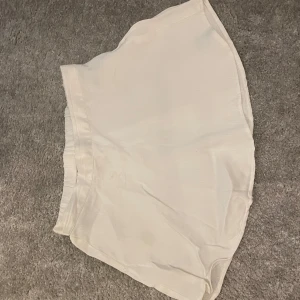 Vit kortkjol från Gina Tricot - Säljer en vit kjol från Gina young. Materialet är likt linnetyg och den är i bra skick.