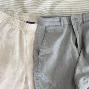 Två par linnebyxor i beige och grått - Säljer två par svala linnebyxor, ett par i beige och ett par i grått. Båda har avslappnad passform, sidfickor och resår i midjan på det beige paret. Perfekta för varma dagar!