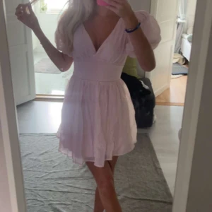 Gina tricot ”bow dress”  - Superfin ljusrosa klänning med v-ringning, puffiga kortärmar och markerad midja. Klänningen har en stor rosett i ryggen. Helt oanvänd och lapparna kvar. Den är nu slutsåld på hemsidan
