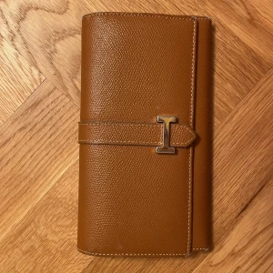 Elegant klassisk clutch kuvertväska i äkta kalvskinn - Fynda en stilren elegant kuvertväska clutch i äkta kalvläder av mycket hög kvalitet.  Mått 11 x 19 cm Material: äkta kalvläder Många fack (några med blixtlås). Kan även användas som portmonnä eller mobilväska. Finns på Östermalm.  Perfekt accessoar för dig som gillar klassisk och tidlös design.