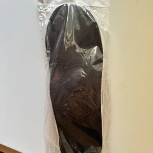 Vita och svarta iläggssulor med röd och gul dämpning - Säljer ett par iläggssulor i vitt och svart med röd och gul stötdämpning under hälen. Perfekta för att ge extra komfort i dina skor. Sulorna är tunna och flexibla, passar de flesta skotyper.