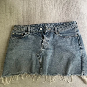 Weekday jeans omsydda till kjol - Säljer en jeanskjol som jag sytt av jeans från Weekday i klassisk blå denim. Kjolen har fransad nederkant, femficksmodell och normal passform. 