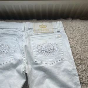 Vita jeansbyxor från Victoria Beckham - Säljer ett par vita boutcut jeans från Victoria Beckham med broderade kronor på bakfickorn och snygga silverfärgade knappar. Mått får man fråga mig om, om man vill de dom på måste man fråga mig. 