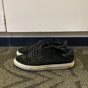 Svarta sneakers från ARIGATO - Säljer ett par svarta sneakers från ARIGATO med vit platt sula och rund tå. Skorna har snörning och är i en stilren design som passar till det mesta. Perfekta för dig som gillar enkel och klassisk stil. Nypris runt 2000 kr, mitt pris 299! Pris går att diskuteras! Hör av er vid minsta lilla fundering🤗