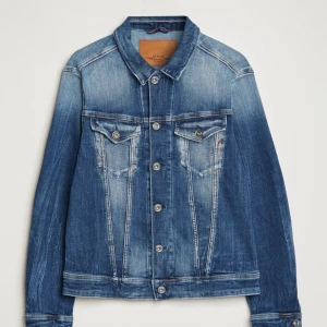 Blå jeansjacka från replay - Klassisk blå jeansjacka från ARKET med knappar framtill och två bröstfickor med lock. Jackan har en rak passform och tydliga sömmar som ger en snygg vintagekänsla. Perfekt att slänga på sig över en t-shirt.