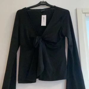 Svart långärmad blus/topp  - Säljer en svart långärmad topp från Gina tricot  med v-ringning och knyt framtill. Passar stl S