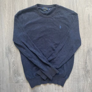 Mörkblå tröja från Polo Ralph Lauren - Säljer en klassisk mörkblå tröja från Polo Ralph Lauren i mjuk pima-bomull. Tröjan har rund halsringning, långa ärmar och den ikoniska broderade loggan på bröstet. Perfekt för en stilren och avslappnad look.