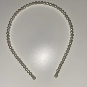 Pärlprydd hårband - Säljer ett stilrent hårband dekorerat med vita pärlor runt hela bågen. Perfekt accessoar för att ge en elegant touch till din frisyr. Hårbandet är böjbart och passar de flesta huvudstorlekar.