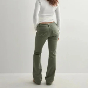 Bootcut gröna jeans nellly  - Snygga gröna bootcut jeans med låg midja och broderade detaljer på bakfickorna. Jeansen har klassisk femficksdesign, två knappar fram och är tillverkade i ett mjukt bomullsmaterial. Perfekt för dig som gillar en chill och trendig look. HELT NYS MED PRISLAPP nypris 700kr