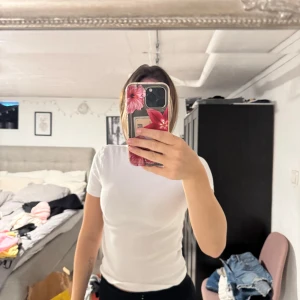 Vit basic t-shirt som är ribbad - En klassisk vit ribbad t-shirt med korta ärmar och rund hals. Modellen är enkel och passar perfekt till jeans eller shorts. Gjord i mjuk bomull för en skön känsla hela dagen.