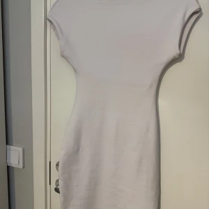 Vit kortärmad klänning från Zara - En enkel och stilren vit kortklänning från Zara i storlek S. Klänningen har korta ärmar, rund halsringning fram och djup v-ringning i ryggen. Den är figurnära och gjord i ett mjukt, stretchigt material som känns bekvämt mot huden. Runt bysten är det ett extra lager tyg som gör att det inte blir så genomskinligt, i övrigt är den inte så genomskinlig heller. Har aldrig använts. 