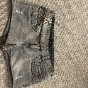 Blå-gråa jeansshorts med slitningar - Snygga jeansshorts med slitna detaljer och flera nitar vid fickorna. Modellen är kort och har dubbla knappar i midjan och coola sömmar. Perfekt för dig som brukar ha 36/38 (jag har 36/S och d passar mig perfekt)