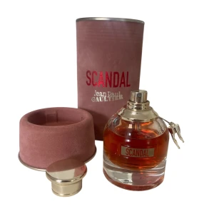 Scandal Eau de Parfum från Jean Paul Gaultier  - Scandal Eau de Parfum från Jean Paul Gaultier i en lyxig rund glasflaska med guldfärgat lock och detaljer. Kommer i en cylinderformad, sammetsliknande rosa förpackning med metallictext. Innehåller 30 ml parfym.