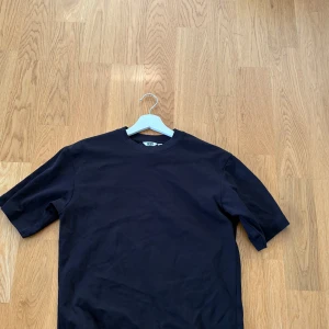 Svart t-shirt från Uniqlo U XS - En stilren svart t-shirt från Uniqlo U i storlek XS. Modellen har klassisk rund hals och korta ärmar. Materialet är mjuk bomull som känns skönt mot huden. Perfekt för dig som gillar minimalistisk och clean look. Köpt för 249kr mitt pris 149kr.