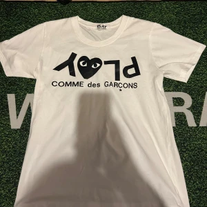 Vit Comme des Garçons Play t-shirt - Säljer en vit t-shirt från Comme des Garçons Play i storlek S. T-shirten har korta ärmar och är gjord i mjuk bomull. På bröstet finns det ikoniska svarta hjärtat.