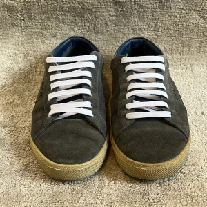 Blå Saint Laurent sneakers i mocka - Snygga blå💙 sneakers från Saint Laurent i strlk 39,5 men passar 40. Skorna är i materialet mocka med blå detaljer vid hälen och vit sula. Skorna har vit snörning och Saint Laurent-logga på sidan. Perfekta för dig som gillar stilrena och exklusiva sneakers med en urban vibe💚Box med kommer!👋
