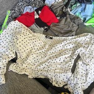 Prickig blus från Bik Bok - Vit blus med svarta prickar från Bik Bok. Blusen har v-ringning, långa puffärmar och smockad resår vid axlar och midja. Volangdetaljer nertill och vid ärmslut.