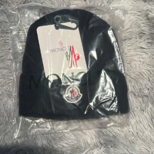 Svart Moncler mössa med logga - Tjena säljer min moncler mössa perfekt för vinter aldrig använd skriv till mig om ni undrar nått😁