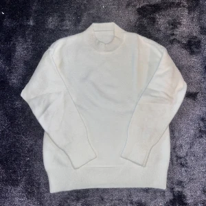 Vit polotröja i mjuk ull - Säljer en stilren vit polotröja med ribbad krage och muddar. Tröjan är gjord i mjuk ull och har en clean, klassisk look som funkar till jeans eller dressade byxor. Perfekt för dig som gillar minimalistisk stil och vill ha något varmt och skönt.