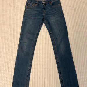 Levi's 512 Slim Taper jeans blå - Säljer ett par klassiska Levi's 512 Slim Taper jeans i blå denim. Modellen har smal passform med avsmalnande ben, fem fickor och snygga kontrastsömmar. Tillverkade i bomull med lite stretch för extra komfort. Perfekta jeans för en clean och stilren look.