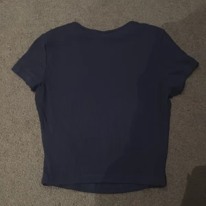 Mörkblå kortärmad topp - En stilren mörkblå topp med korta ärmar och diskret ribbad struktur. Skriv för fler bilder å info. (öppet pris) Skriv innan du köper. 