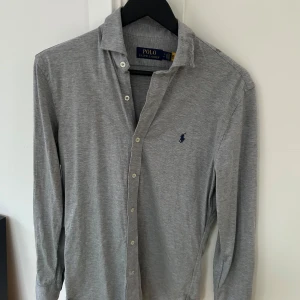 Grå långärmad skjorta Polo Ralph Lauren - Snygg grå långärmad skjorta från Polo Ralph Lauren i mjuk bomull. Perfekt för en clean och stilren look. 