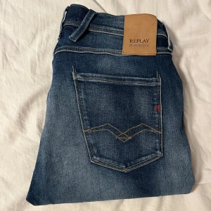 Replay Hyperflex Anbass jeans blå - Snygga Replay Hyperflex Anbass jeans i mörkblå tvätt med slitningar och klassiska kontrastsömmar. Modellen har fem fickor, normal midja och raka ben. Stretchigt material för extra komfort och passform. Perfekta för en avslappnad och trendig look.(W30,L30) Tveka inte att fråga om ni vill ha fler bilder eller undrar något, Mvh Olle 