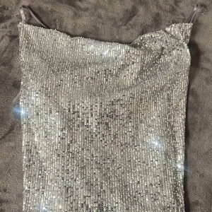 Glittrigt Linne från Zara - Säljer ett glittrigt silverfärgad linne från Zara med tunna axelband!💕 