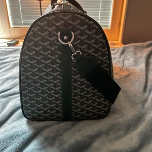 G väska  - Säljer en snygg och rymlig resväska från Goyard i grönt med deras ikoniska grafiska mönster. Väskan har silverfärgade dragkedjor, bred axelrem och detaljer i grönt skinn. Perfekt för weekendresor och har ett stort innerfack med extra ficka.