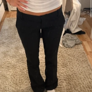 Svarta bootcut kostymbyxor - Snygga svarta kostymbyxor med bootcut passform och låg midja. Byxorna har klassiska fickor fram och bak. Perfekta för dig som gillar en stilren look med lite utsvängda ben. Passar till både sneakers och klackar.