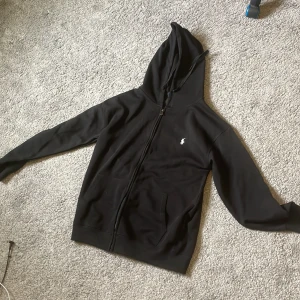 Svart hoodie från Polo Ralph Lauren - Svart zip hoodie från Polo Ralph Lauren, knappt använd inte ens gått igenom tvätt
