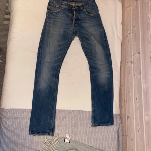 Nudie Regular Ralf Jeans - Säljer ett par klassiska Nudie jeans i modellen Regular Ralf med snyggt slitna detaljer. Modellen har normal midja och raka ben med en något smalare passform. Perfekta till sneakers och hoodie för en chill look. 