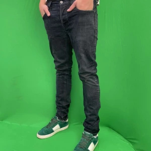 Nudie jeans - Snygga svarta skinny jeans från Nudie Jeans med klassisk femficksdesign och diskreta slitningar. Storlek 32W 34L Jeansen har en smal passform och är tillverkade i stretchig bomullsdenim för en bekväm känsla. Perfekta för dig som gillar en modern och stilren look.
