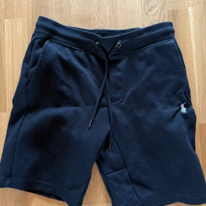 Svarta shorts från Polo Ralph Lauren - Snygga svarta shorts från Polo Ralph Lauren med slim fit och klassisk broderad logga på benet. Mjukt bomullsmaterial, snörning i midjan och fickor både fram och bak. Perfekta för chill dagar och sommarhäng.