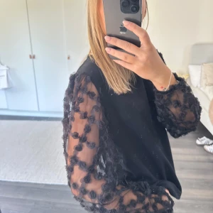 Svart topp med transparenta blommiga ärmar - Blus från Vero Moda med blommiga armar. Storlek L men passar mig som har xs/s