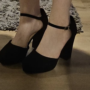 Svarta pumps med rem - Säljer dessa klackskor, tycker de är för höga för min smak. Dessa kommer med ett band som man kan justera vilket gör så att klackskorna sitter på fötterna och inte ramlar av! Jag har använt de en gång, men jag ramlade väldigt mycket med dem så de har slitage (se bilder). Men dessa går att fixa om man skulle vilja det. Skorna har stabil klack vilket gör de lätta att gå i! Helt nya annars!