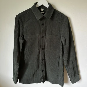 Mörkgrön Arket manchester overshirt strl 46 - Snygg mörkgrön Arket overshirt i mjuk manchester. Regular fit med raka linjer, två stora bröstfickor och knappar framtill. Långärmad och tillverkad i 100% bomull. Perfekt att slänga över en t-shirt för en chill look. 1E7