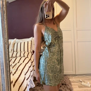 Grön silke/siden klänninh med snörning - Supersöt grön klänning från Zara Klänningen har smala axelband, v-ringning och snygg snörning framtill som ger en rynkad effekt. Materialet är glansigt silke/satin.