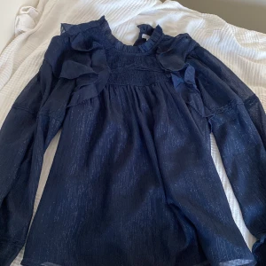 Mörkblå glittrande volangblus  - Supersnygg mörkblå blus med volangdetaljer på axlarna och långa ärmar. Köpt från Gina Tricot. Endast använd en gång. Pris kan diskuteras 💕