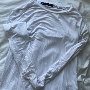 Vit långärmad tröja från 157 - En basic vit långärmad tröja från 157 i mjuk bomull. Enkel och clean design med rund halsringning, perfekt att styla med jeans eller under en skjorta. Snygg och tidlös modell som funkar året runt.