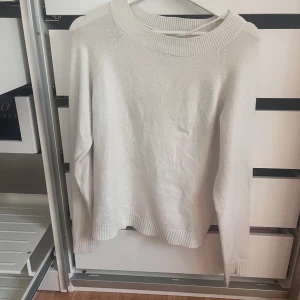 Vit stickad tröja från Vero Moda - Snygg vit stickad tröja från Vero Moda i storlek S. Tröjan har en bred ribbad rund halsringning och långa ärmar med ribbade muddar. Perfekt för att skapa en clean och chill look, funkar till jeans eller kjol. Materialet är mjukt och skönt mot huden.