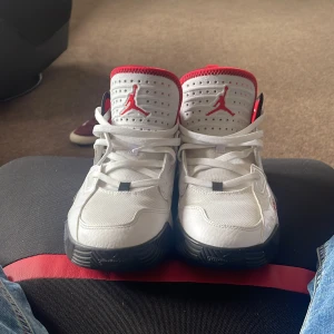 Nike Air Jordan 23 vita och röda sneakers - Säljer ett par Nike Air Jordan 23 sneakers i vitt med röda och svarta detaljer. Skorna har klassisk snörning, perforerad tå och svart yttersula med röd Jumpman-logga. Ovandelen är i syntet och mesh för en sportig vibe. Perfekta för dig som gillar streetstyle. Bara skor följer med vi köp av skorna 