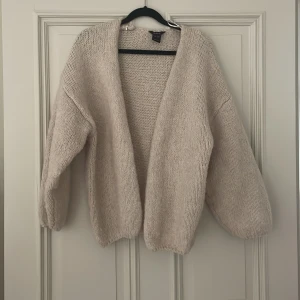 Stickad kofta - Mysig beige stickad kofta från Lindex som är slusåld i storlek XS/S. Koftan är öppen framtill, har långa ärmar och är tillverkad i en blandning med återvunnen polyester. Perfekt för lager-på-lager och chill vibes.