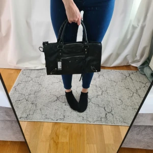 Svart handväska  - Svart väska i stil city bag. Axelrem medföljer. Ca 34x20 cm.