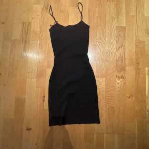 Svart tight klänning från Mango - En svart, tight och enkel klänning från Mango med smala axelband och rak passform. Klänningen är kort och har en stilren look som passar perfekt när du vill känna dig extra snygg. Materialet känns stretchigt och följsamt. Aldrig använd 